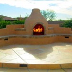 Outdoor Fireplace feature in front of green bushes