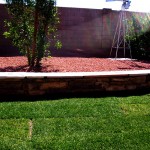 freshly laid sod in front of mini brick wall with bushes and windmill