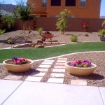 Finished landscaped yard with green grass surrounded by stone and trees with two flower pots in front