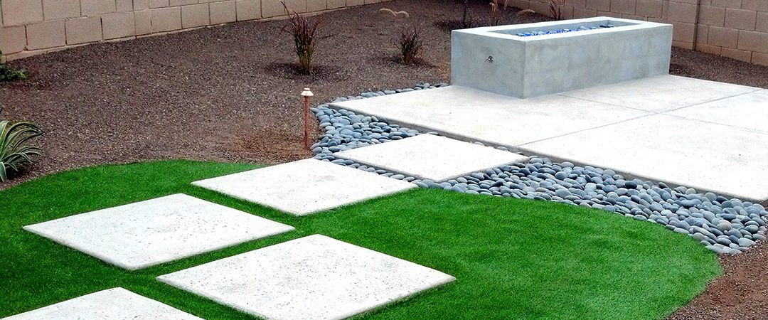 backyard with stone and concrete pavers with grass and dirt by stone fireplace